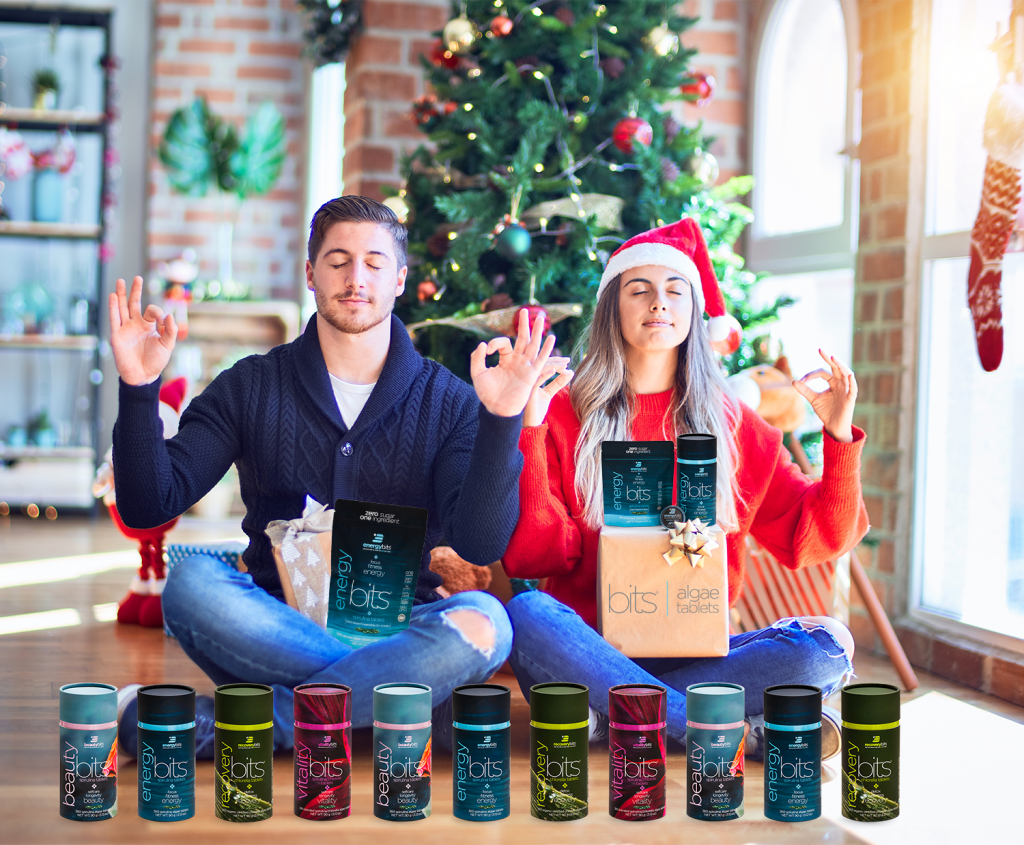 man and woman doing yoga in front of Christmas tree with ENERGYbits products